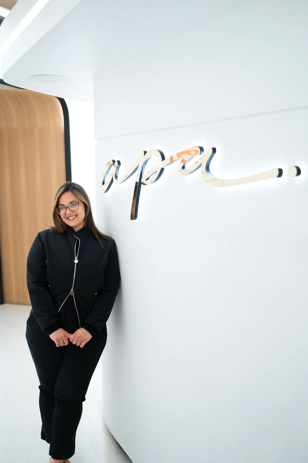 Dr. Andi-Jean Miro beside the illuminated apa sign at Apa Aesthetic, Beverly Hills