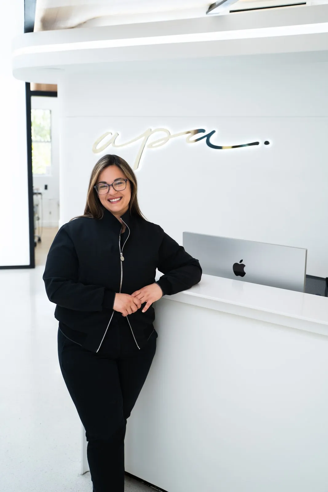 Dr. Andi-Jean Miro at the reception desk under the apa sign, Apa Aesthetic Beverly Hills
